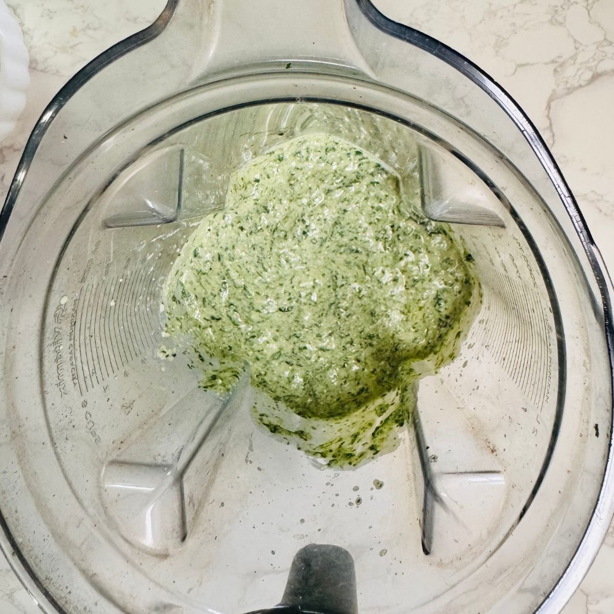 Blended spinach ricotta lasagna filling with whole milk ricotta cheese, fresh spinach, and garlic in a clear blender jar.