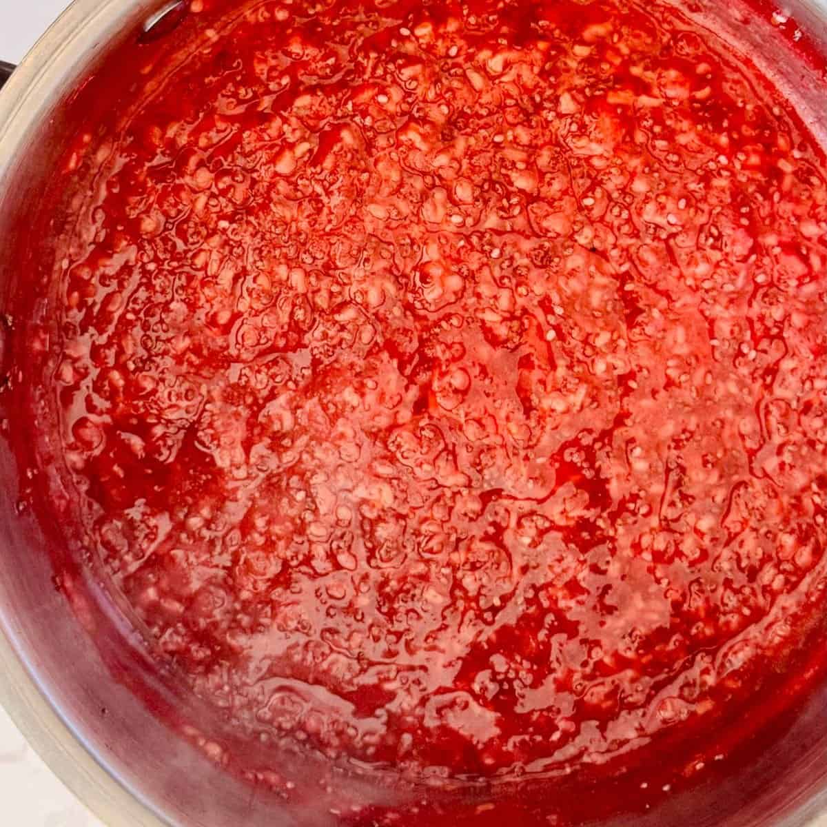 Making Raspberry Chia Jam in a pot with bubbling.